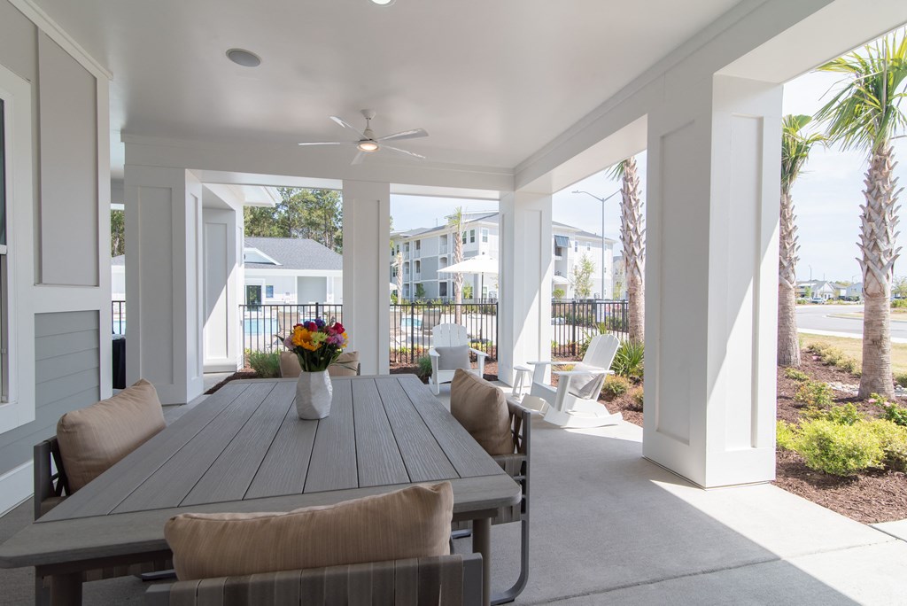 a patio with a wooden table and chairs and a ceiling fan
