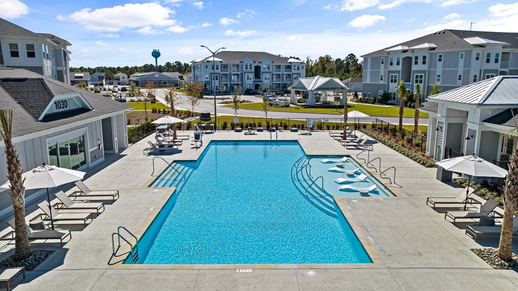 a swimming pool with chairs and umbrellas at the resort on a sunny day