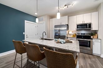 a kitchen with white cabinets and a large island with a granite countertop