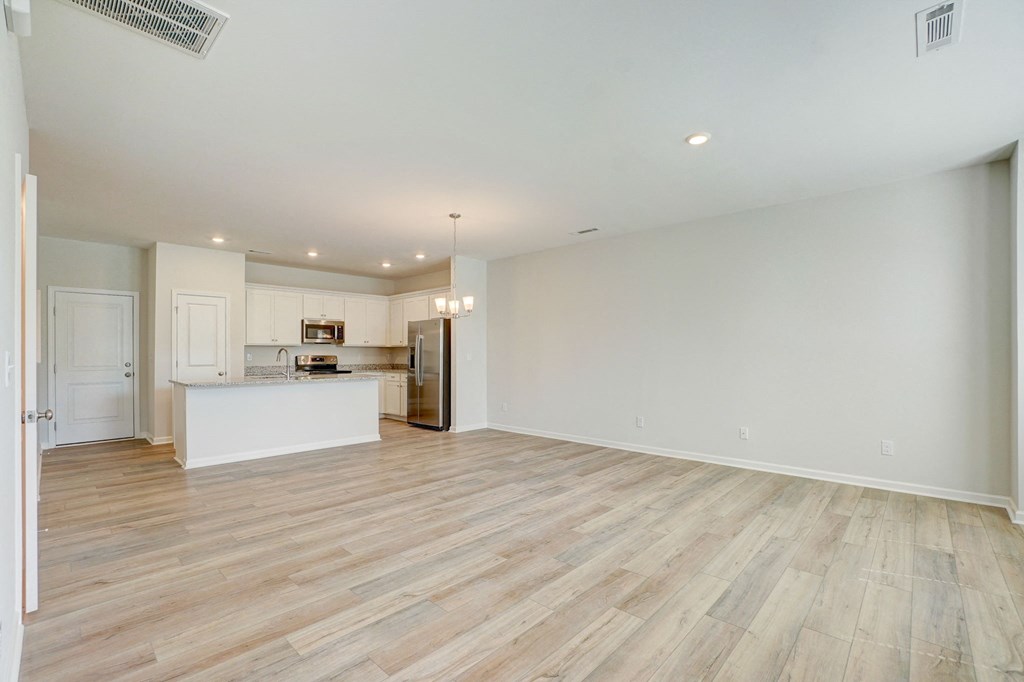 a living room with a kitchen and a hard wood floor