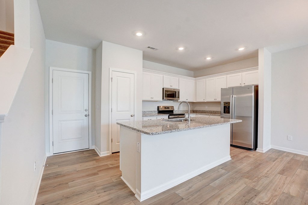a kitchen with an island and a stainless steel refrigerator