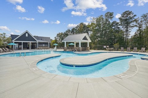 a resort style pool with chairs around it and a house in the background