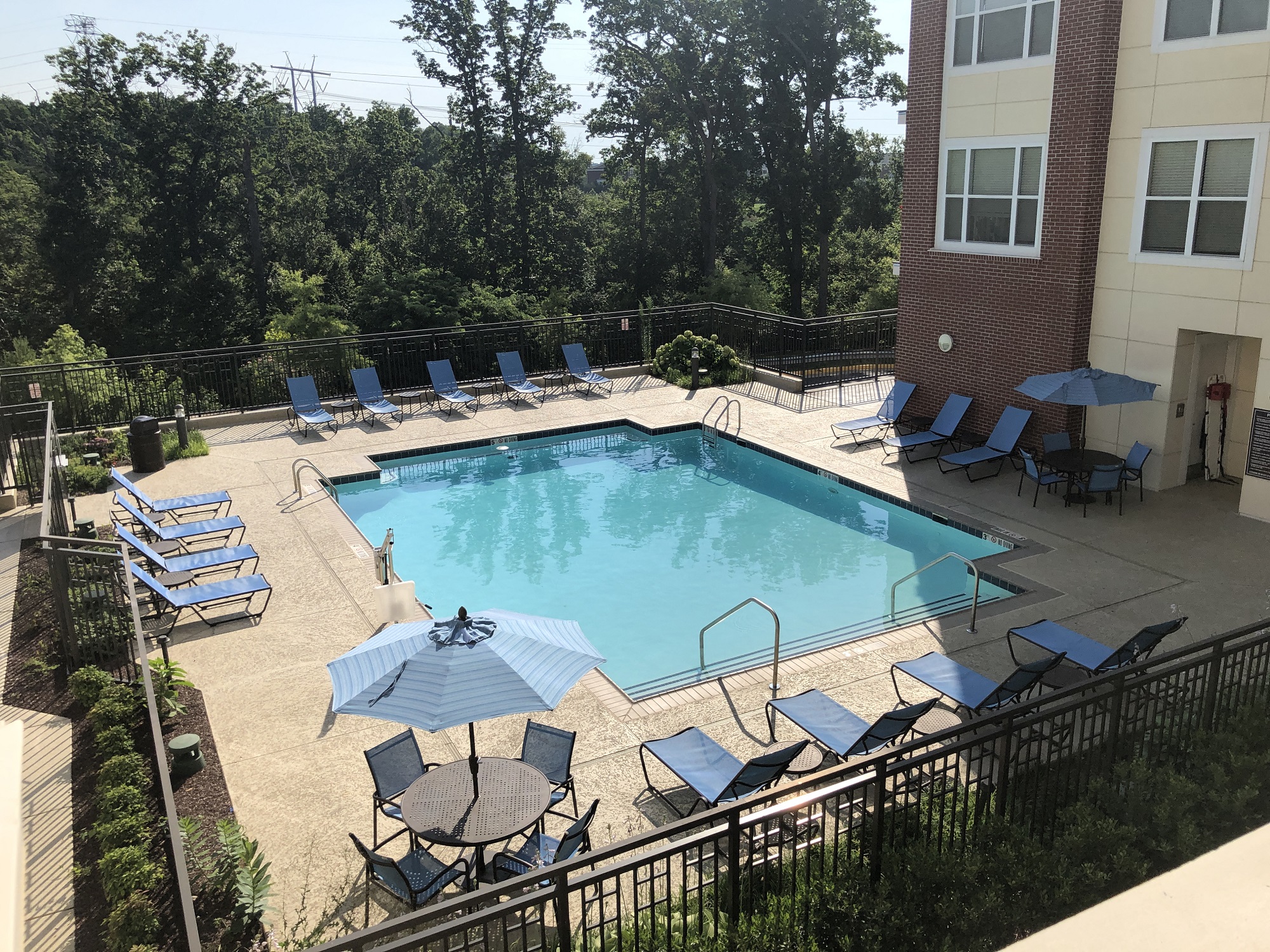 a resort style pool with blue chairs and umbrellas