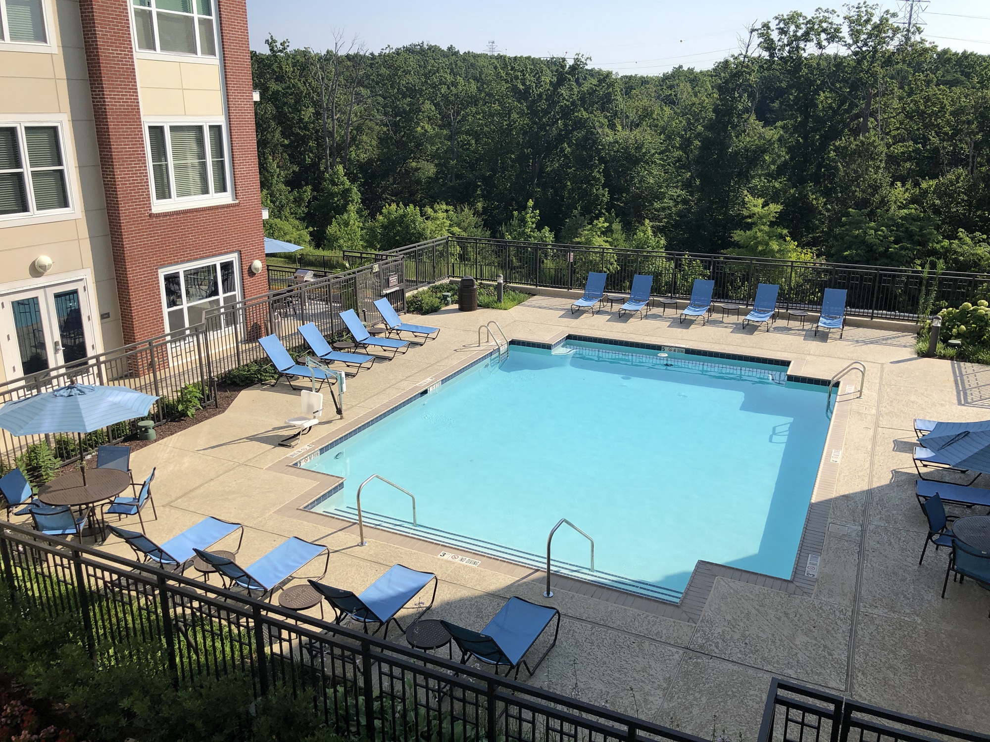 an aerial view of a swimming pool with blue chairs and a building