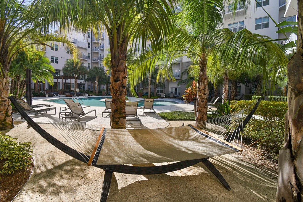 A hammock is strung between two trees in a courtyard.