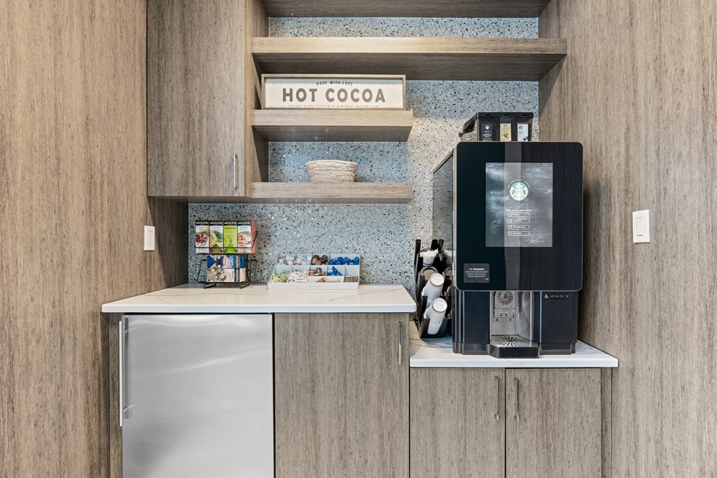 A modern kitchen with a hot cocoa sign on the shelf.