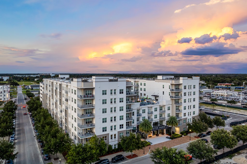 A large white apartment building with a sunset in the background.