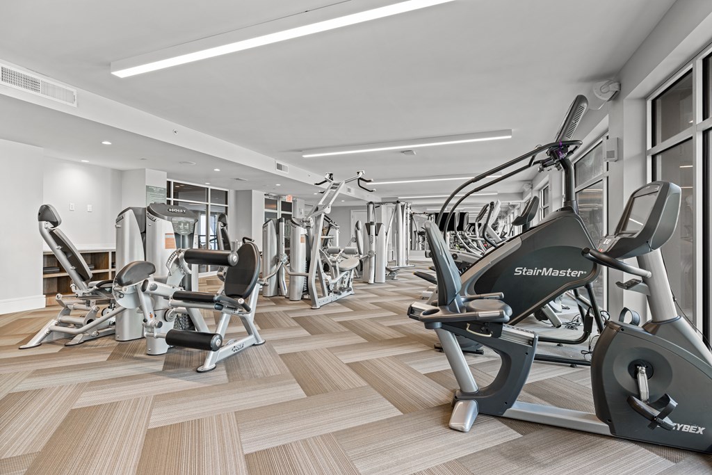 A gym with a variety of exercise equipment including treadmills, stationary bikes, and weight machines.