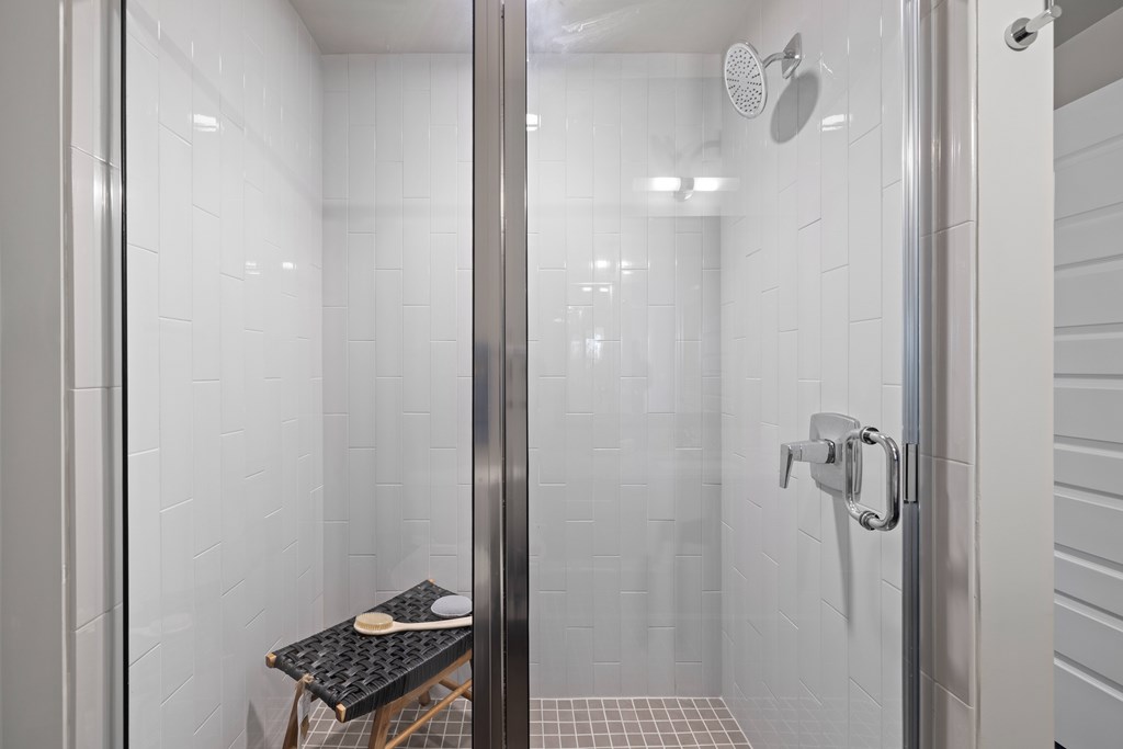 A glass shower door with a black tray on a wooden stand.