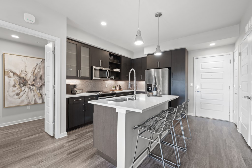 A modern kitchen with a white island and dark brown cabinets.