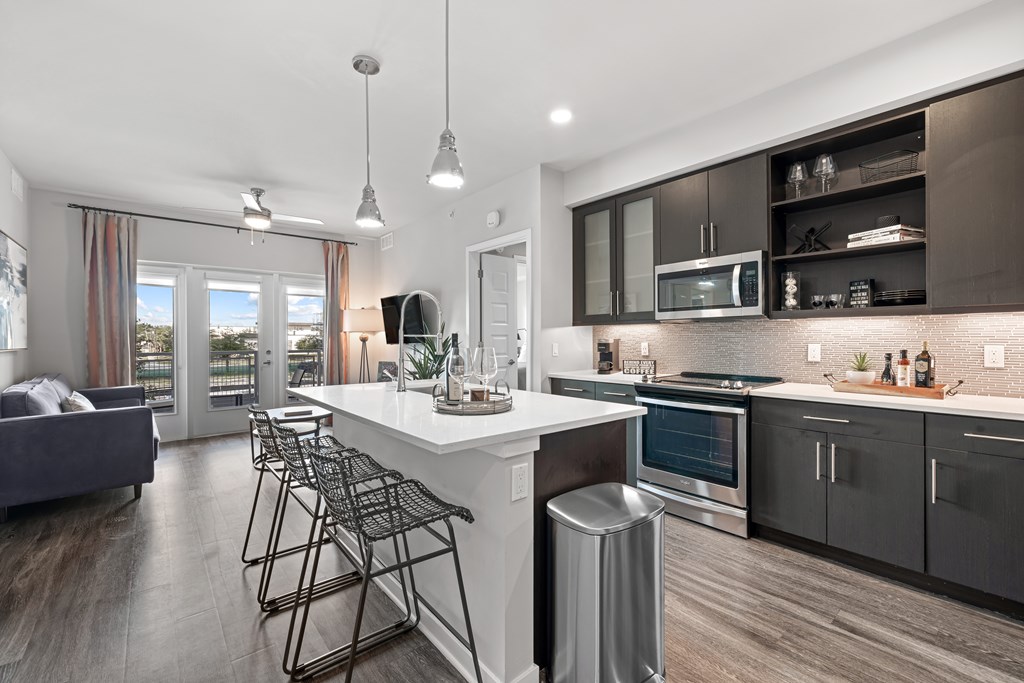 A modern kitchen with a white island and black bar stools.