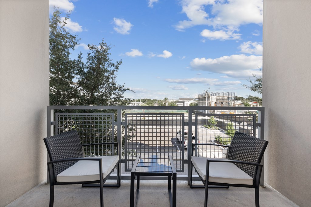 A balcony with a table and chairs overlooking a parking lot.