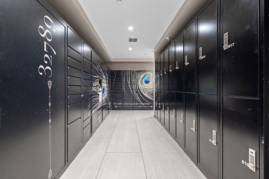 A long hallway with black lockers on the side and a white floor.