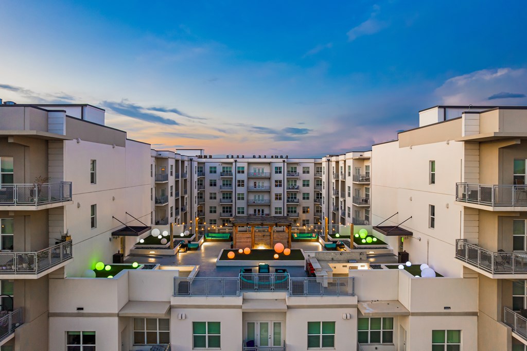 A view of apartment buildings with balconies and a pool in the foreground.