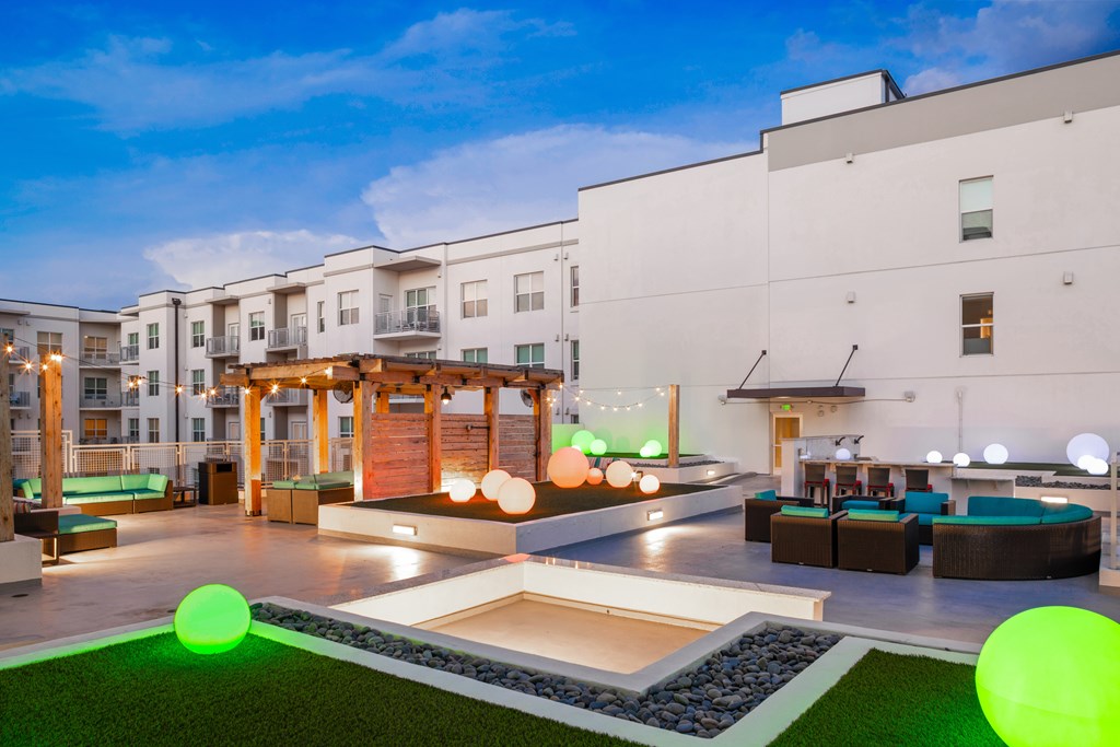 A modern courtyard with a grassy area, seating, and a wooden pergola.