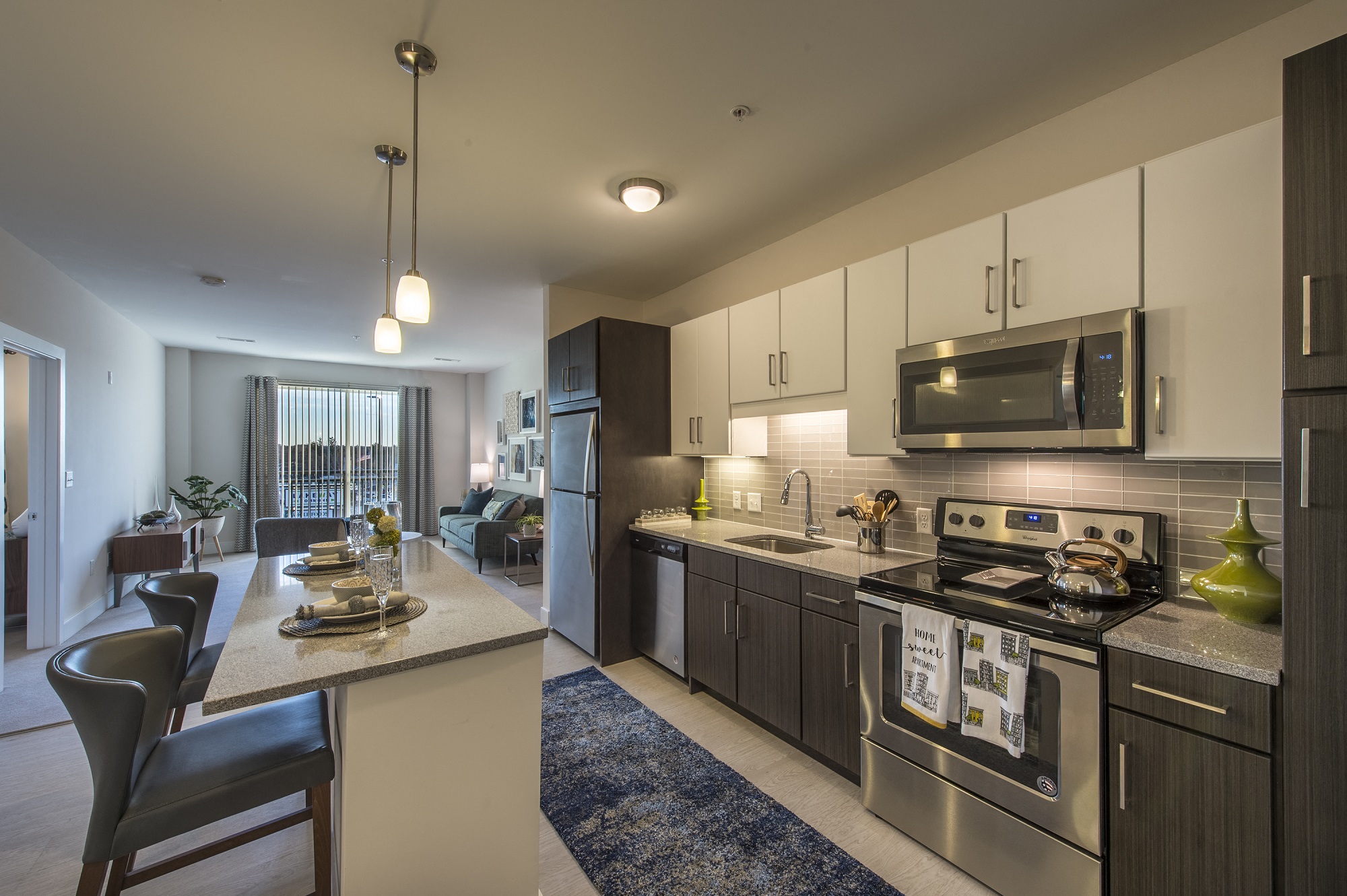an open kitchen and living room with stainless steel appliances and a table