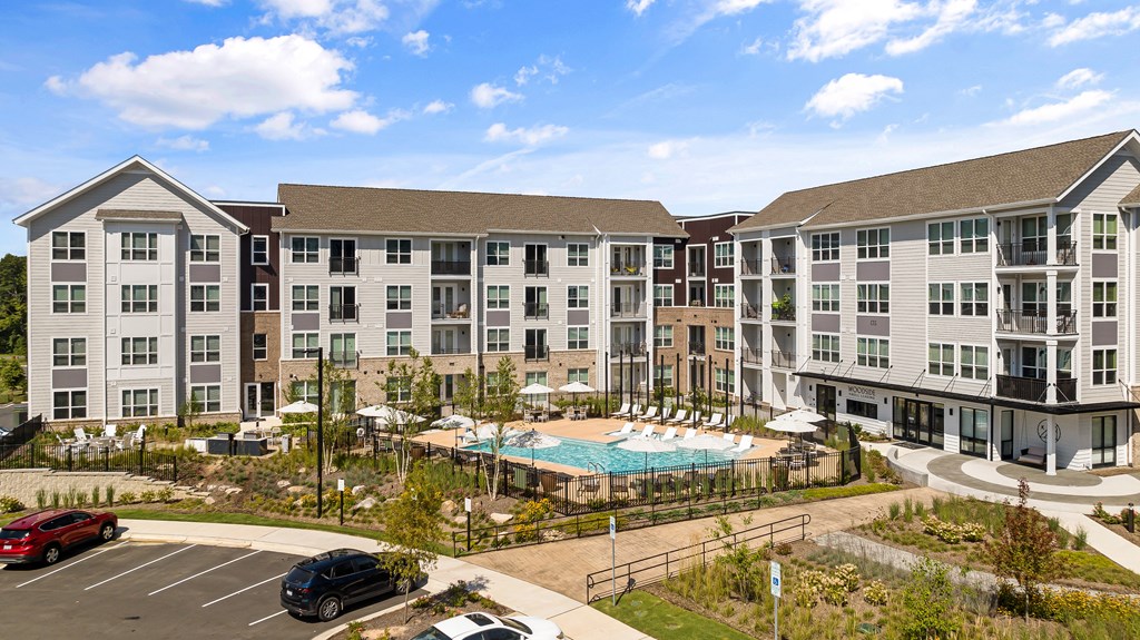 an exterior view of an apartment complex with a swimming pool