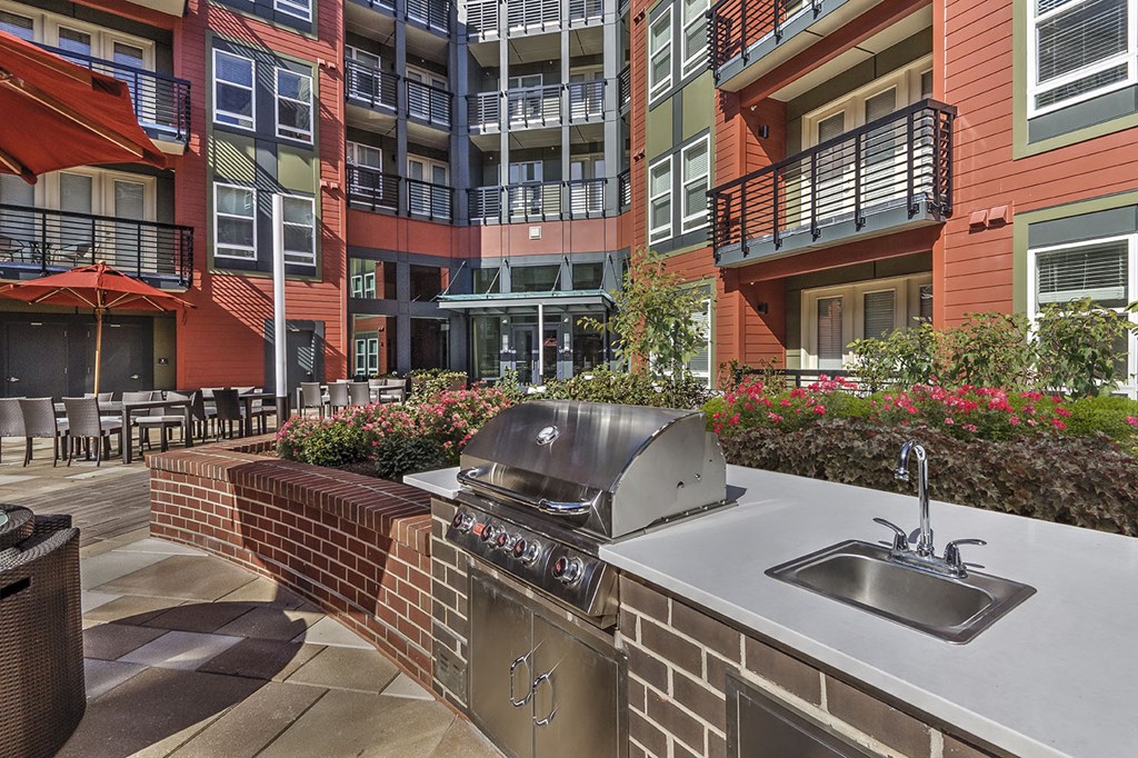 a patio with a grill and a sink in front of an apartment building
