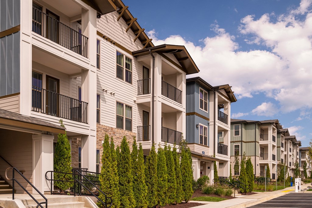 a row of apartment buildings with balconies and green trees