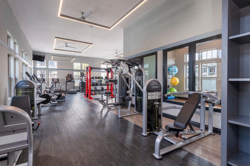 a gym with weights and cardio equipment and windows