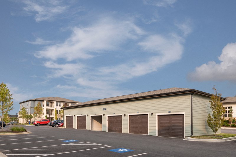an empty parking lot in front of a building with three garage doors