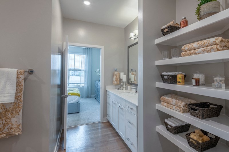 a bathroom with white shelves and a sink and a mirror
