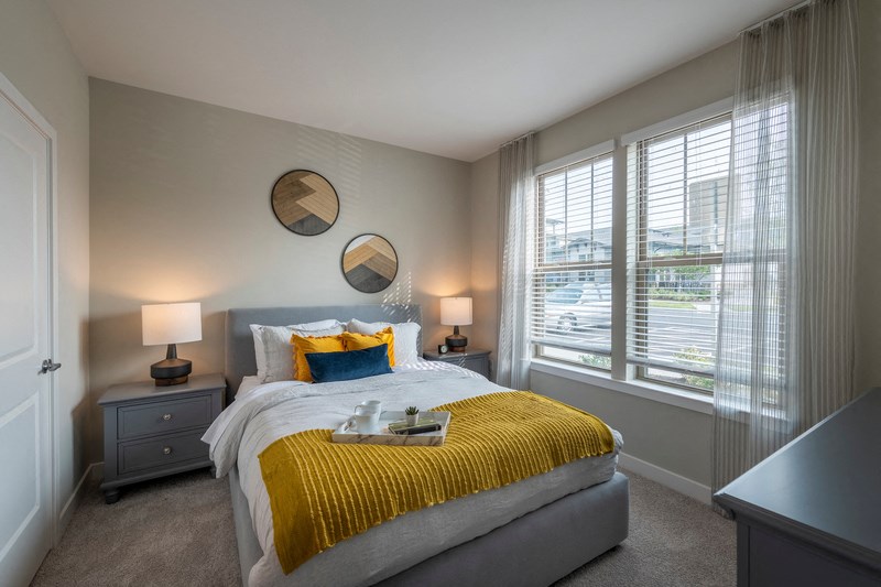 a bedroom with a large bed and two windows