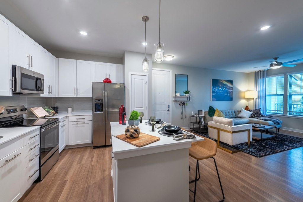 a kitchen and living room with white cabinets and stainless steel appliances