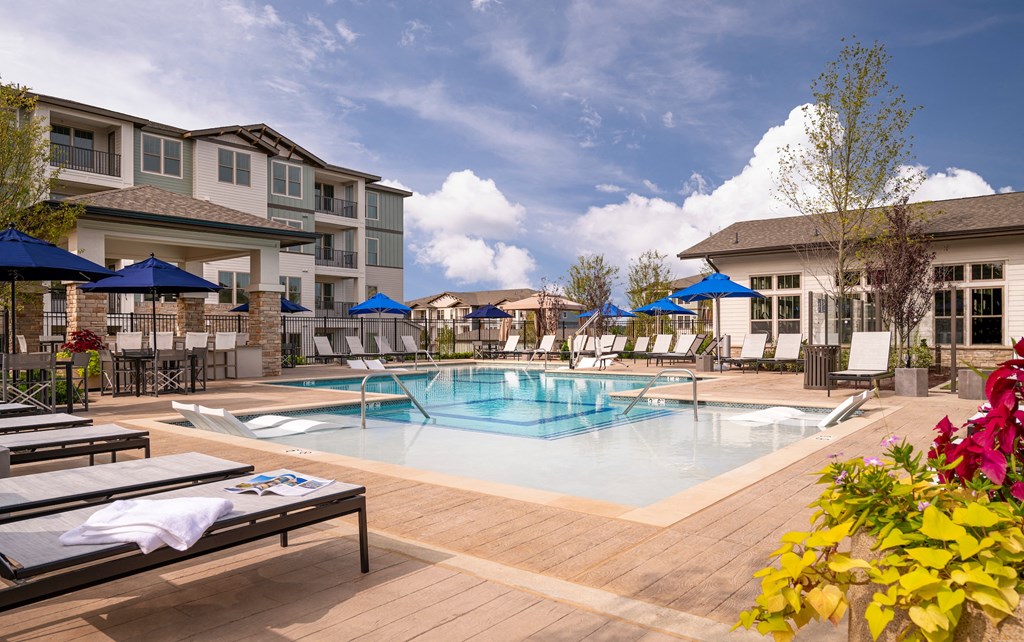 a swimming pool with tables and umbrellas in front of a building