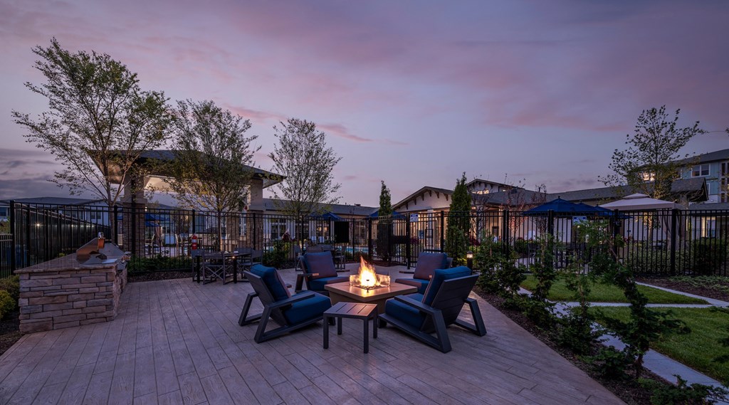 a backyard patio with a fire pit and chairs