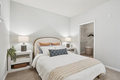 A bedroom with a large bed and a nightstand with a lamp.