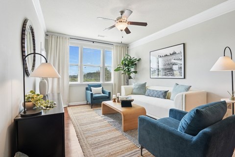 A living room with a white couch, blue chairs, and a coffee table.