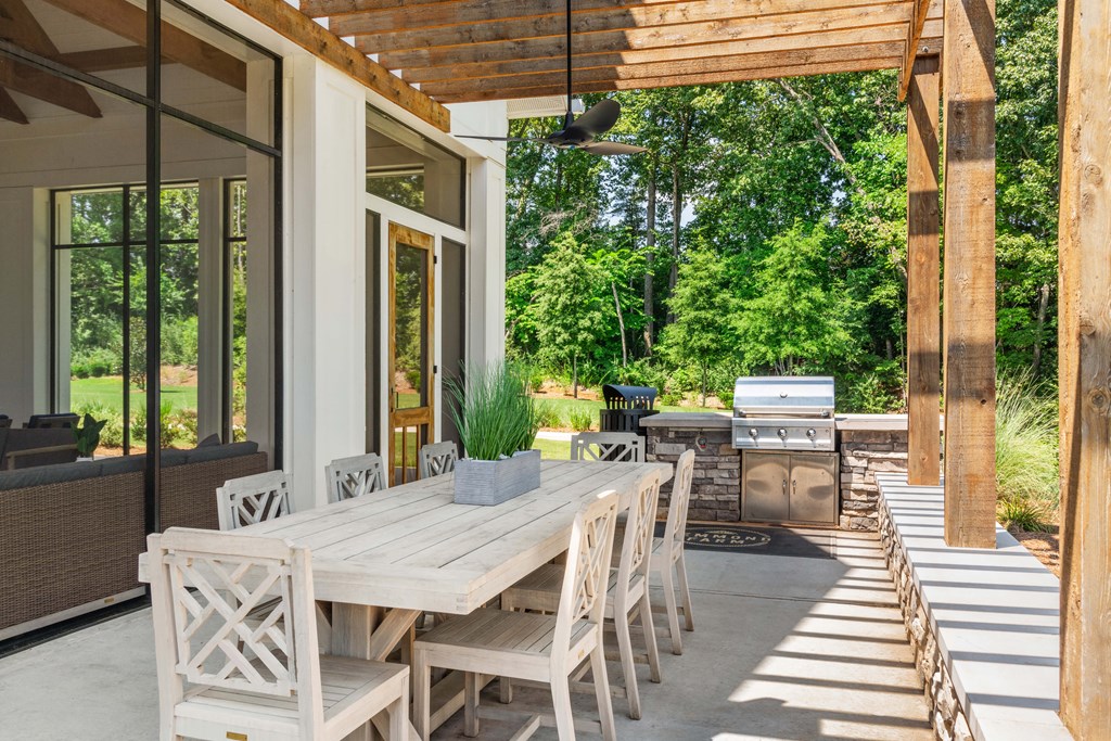 a patio with a wooden table and chairs and a grill