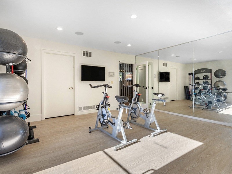 a workout room with bikes and mirrors in a home gym