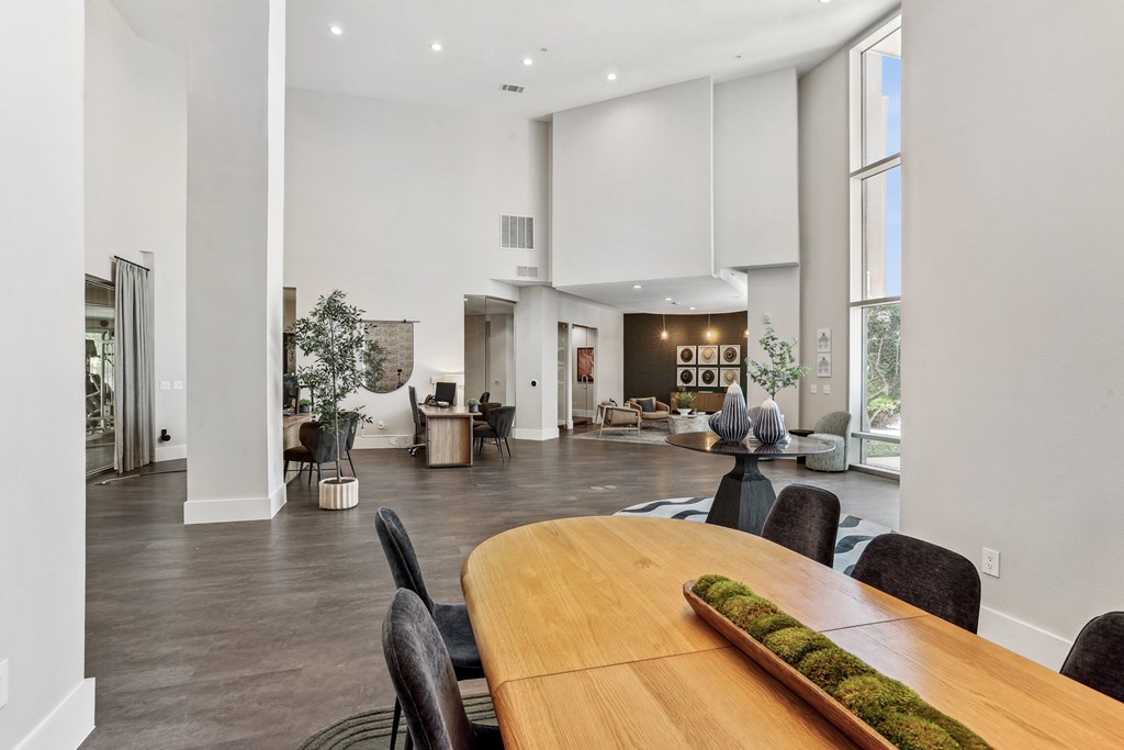 A modern dining room with a long wooden table and black chairs.