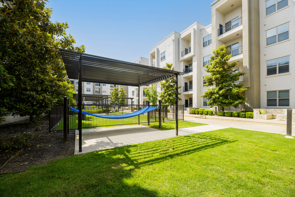 A playground with a blue rope is surrounded by apartment buildings.