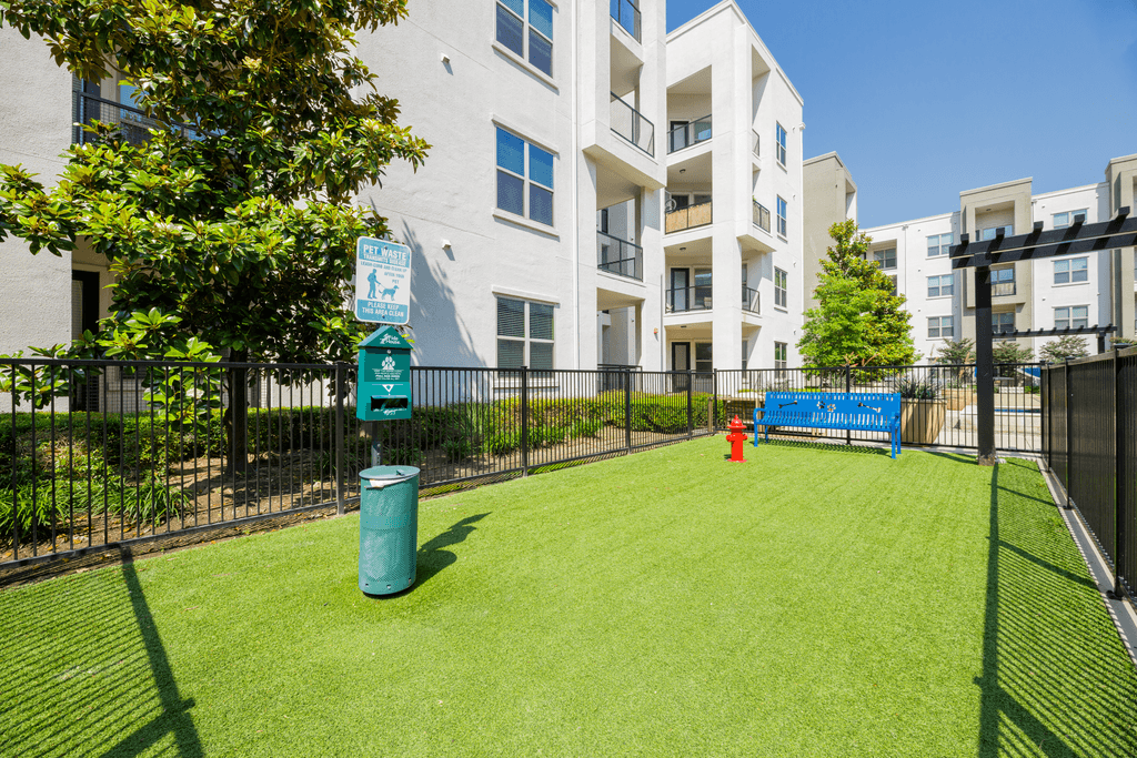 A green space in front of a white building with a blue sign and a red fire hydrant.