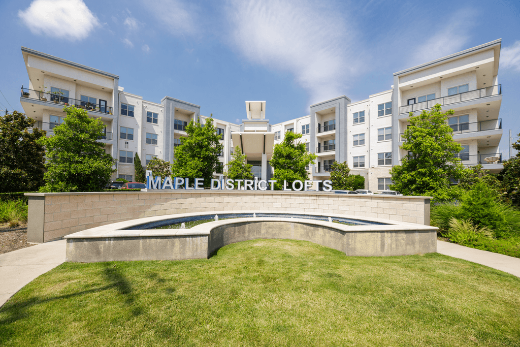 Maple District Lofts is a modern apartment complex with a landscaped front yard.