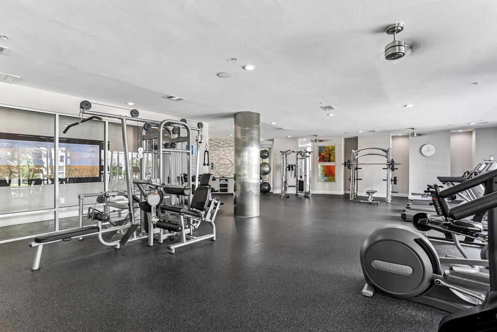 A gym with a variety of equipment including treadmills, weights, and exercise machines.