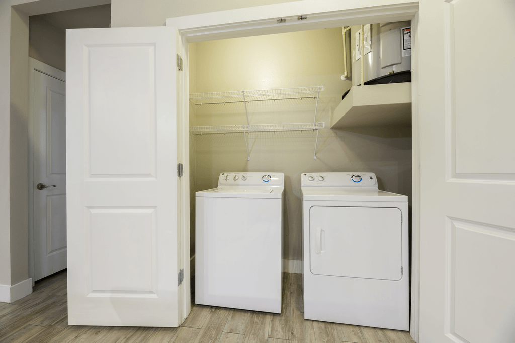A white door opens to a laundry room with a washer and dryer.