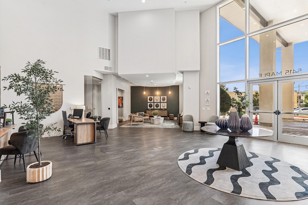 A modern office space with a large desk, chairs, and a tree.