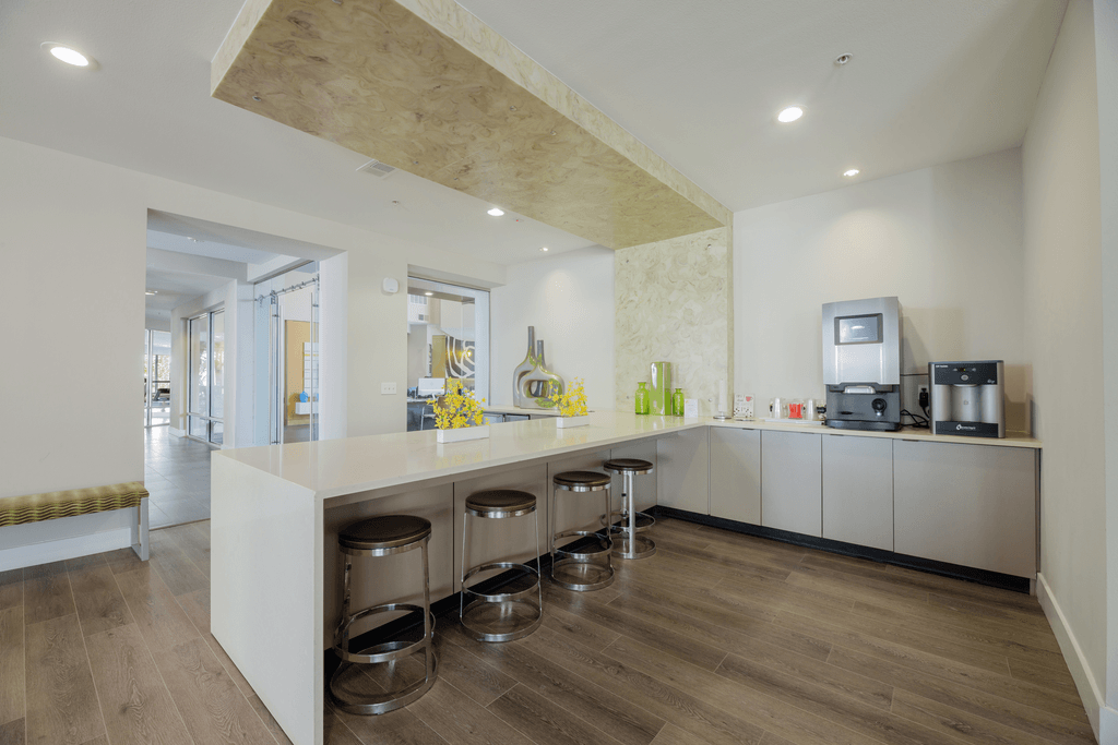 A kitchen with a white counter and stools.