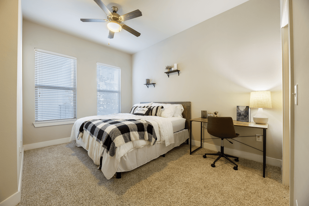 A bedroom with a bed, desk, and chair.