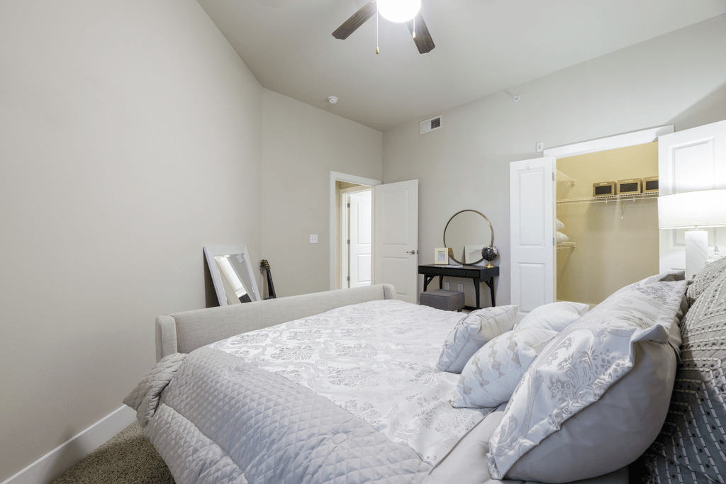A bedroom with a large bed and a ceiling fan.