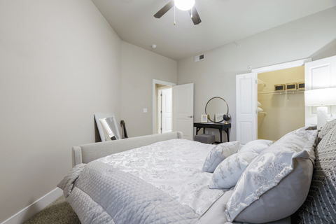 A bedroom with a large bed and a ceiling fan.