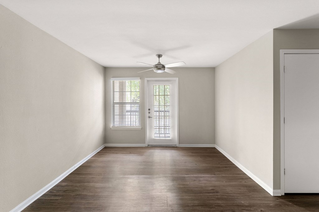 an empty living room with white walls and a ceiling fan