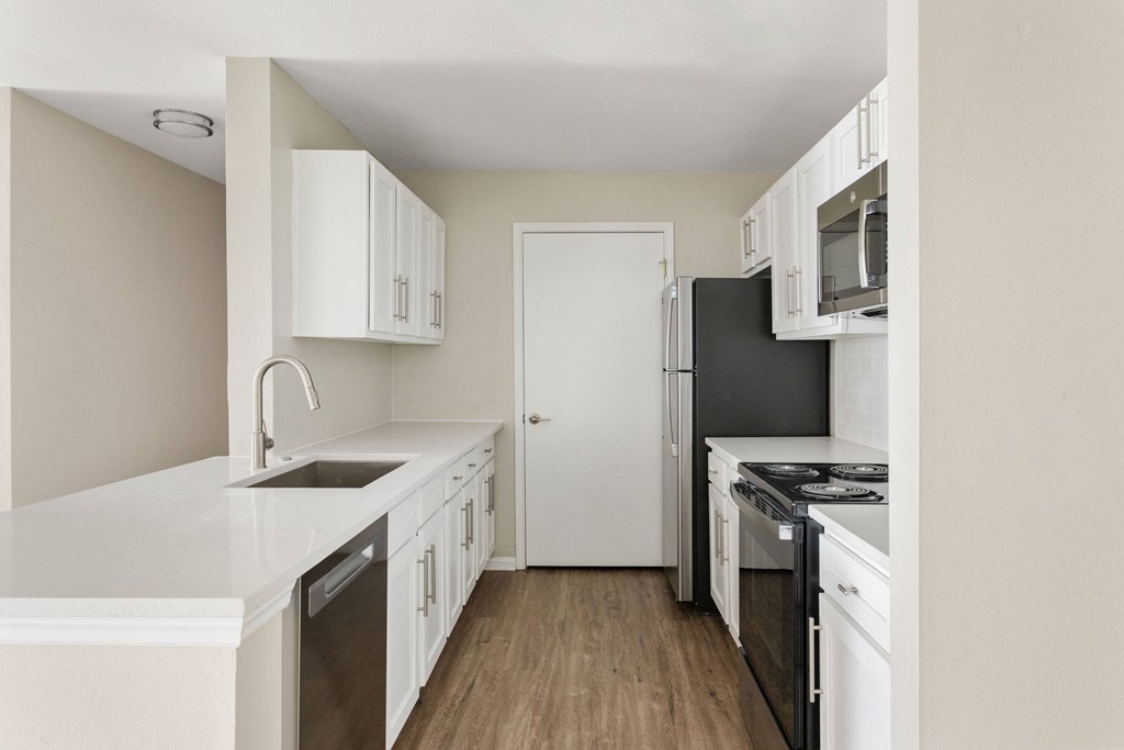 an empty kitchen with white cabinets and stainless steel appliances