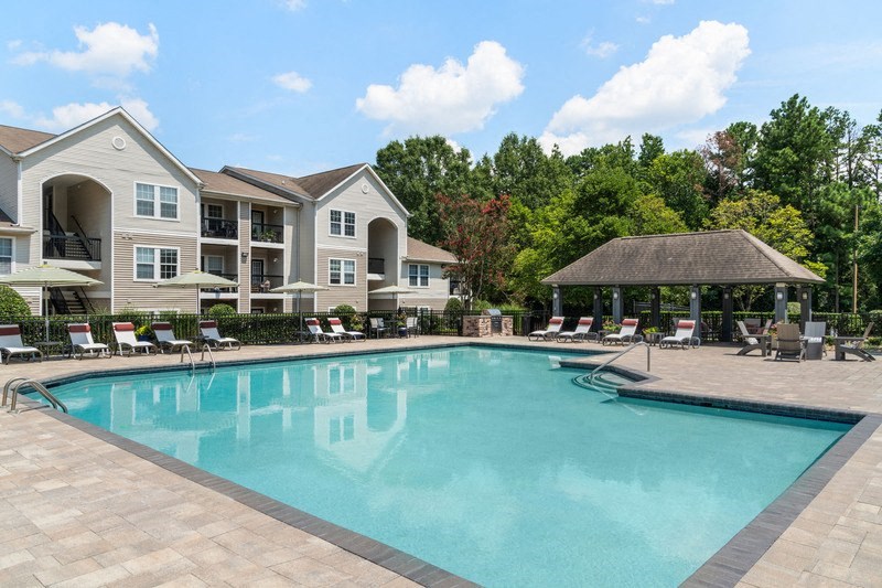 a swimming pool with chaise lounge chairs and a gazebo in front of a
