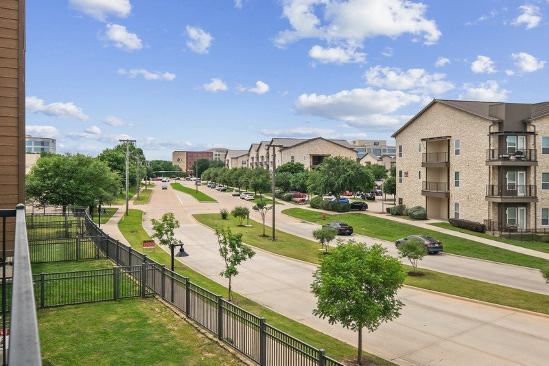 A view of a residential street with cars parked on the side.