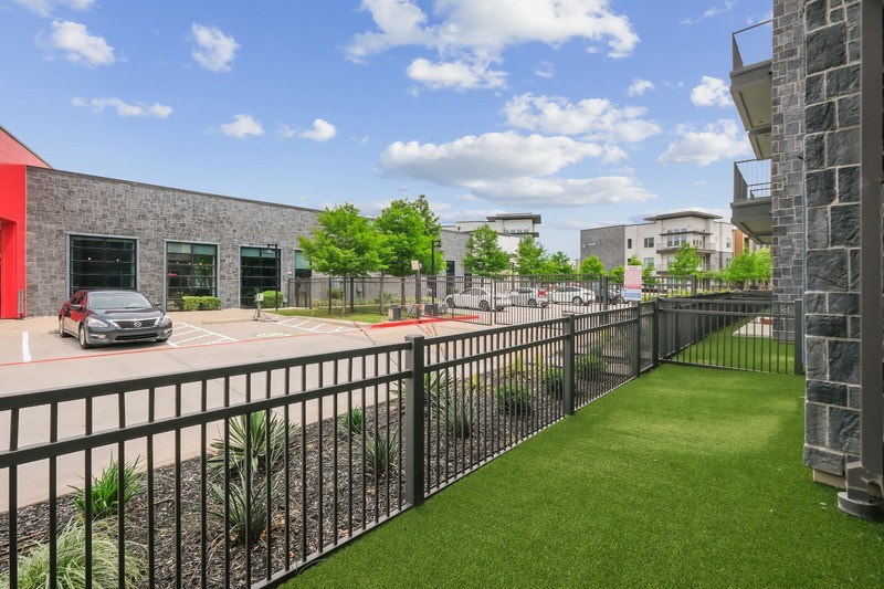 A view of a parking lot with a red building and a black fence.